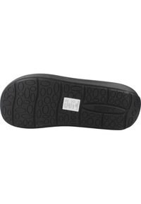 Suela de zapato de goma negra con un patrón texturizado, que presenta una variedad de surcos ovalados y circulares para tracción y un logo en el centro.