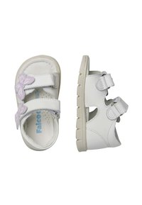 Sandalias blancas con un acento de mariposa en púrpura, doble correa de velcro, parte superior de cuero suave y suela exterior de goma texturizada para un mejor agarre.