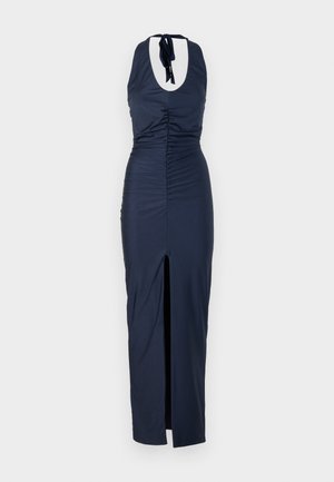 Navyblaues Neckholderkleid mit geraffter Textur, seitlichem Schlitz und offenem Rückendetail. Der Stoff ist glatt und passt sich der Silhouette an.
