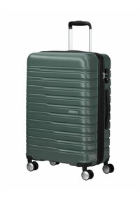Valigia rigida di colore verde scuro, caratterizzata da scanalature verticali, manico telescopico e ruote multidirezionali. Chiusura con zip sul lato.