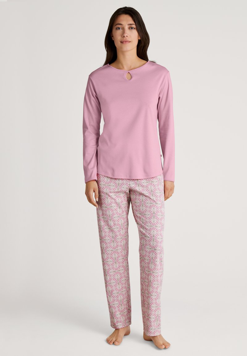 Rooze lange mouwen top met een keyhole halslijn, gecombineerd met gebloemde pyjamabroek in roze en witte kleuren. Zachte stof, relaxte pasvorm.