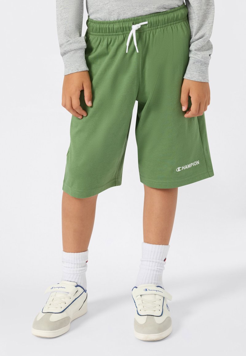 Groene shorts met een elastische tailleband en een witte trekkoord, met zijzakken en een wit "Champion" logo aan de zoom.