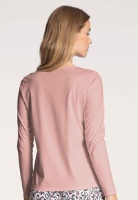 Long-sleeve pink top made of soft material, featuring a round neckline and a simple design. The model is shown from the back.