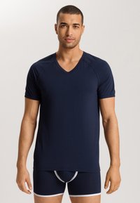 Marineblauwe v-hals t-shirt gemaakt van zacht materiaal, korte mouwen, en een naadloos ontwerp, gedragen met bijpassende marineblauwe boxershorts met witte afwerking.