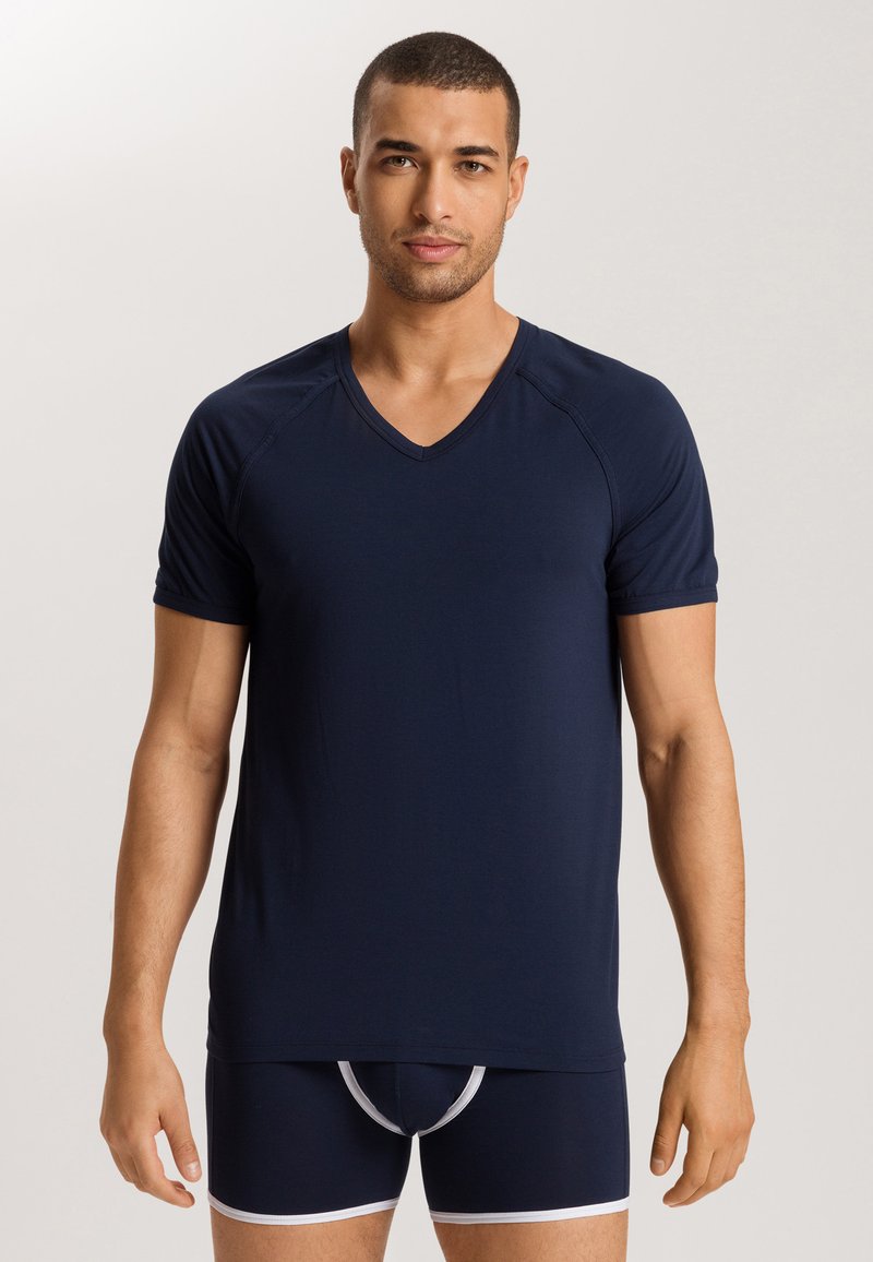 Marineblauwe v-hals t-shirt gemaakt van zacht materiaal, korte mouwen, en een naadloos ontwerp, gedragen met bijpassende marineblauwe boxershorts met witte afwerking.
