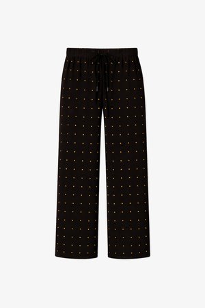Černé volné kalhoty s elastickým pasem, šňůrkami na stažení a vzorem malých rovnoměrně rozmístěných zlatých teček.