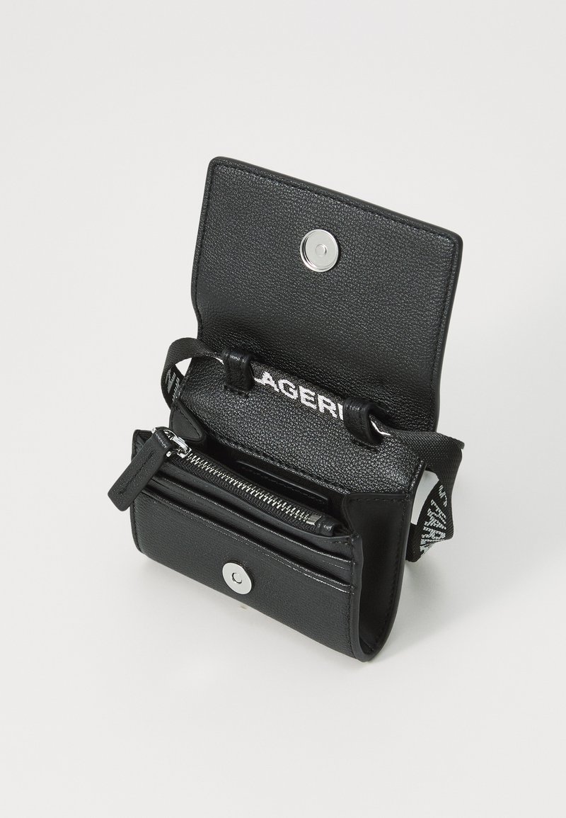 Sac en cuir noir avec une finition texturée, doté d'une fermeture à pression, d'une poche zippée et d'une sangle avec du texte imprimé à l'intérieur.