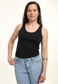 Zwarte mouwloze tanktop van katoen, gecombineerd met lichtblauwe high-waisted denim jeans. Eenvoudig ontwerp met een ronde hals.