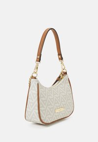Sac à main blanc avec un motif géométrique beige, des accents en cuir marron et une plaque en or. Doté d'une seule bandoulière et d'une fermeture éclair.