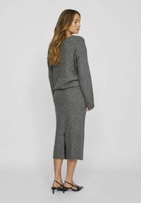 Conjunto de punto acanalado gris que incluye un top de manga larga y una falda hasta la rodilla con una abertura en la parte trasera y una textura suave.