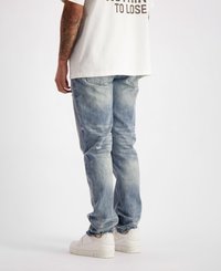 Lichtblauwe denim jeans met een vervaagd uiterlijk, lichte slijtage en een rechte snit, gecombineerd met witte sneakers en een losse, witte graphic t-shirt.