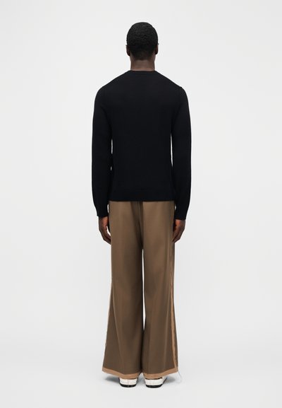 Black long-sleeve sweater and loose brown pants with cream trim. Smooth texture, simple design, and no visible patterns or logos.