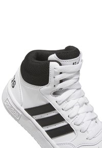 Białe wysokie trampki z czarną siateczkową kołnierzem, trzema czarnymi paskami po bokach i teksturowaną gumową podeszwą. Zaprojektowane do wszechstronnego noszenia.
