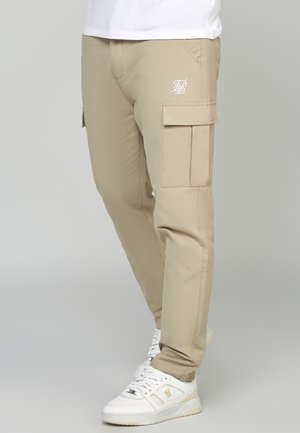 Beige Cargo-Hosen mit Reißverschluss-Taschen, elastischem Bund und Logo-Detail. Gefertigt aus einem glatten Stoff, mit schmal zulaufendem Schnitt und geradem Bein-Design.