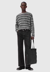 Grijs en zwart gestreepte gebreide trui, zwarte spijkerbroek, zwarte leren laarzen en een getextureerde zwarte schoudertas. Outfit heeft een casual pasvorm.