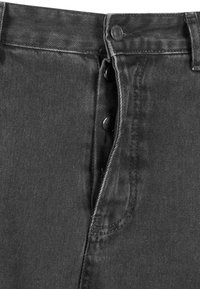 Pantalones de denim negros con cintura alta, cierre de botón y costuras contrastantes a lo largo de las costuras, con una textura suave.