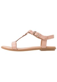 Vaaleanpunainen nahkasaapas, jossa on T-nauha, säädettävä solki, tasapohja ja minimaaliset korostukset. Sileä pinta ja yksinkertainen siluetti.