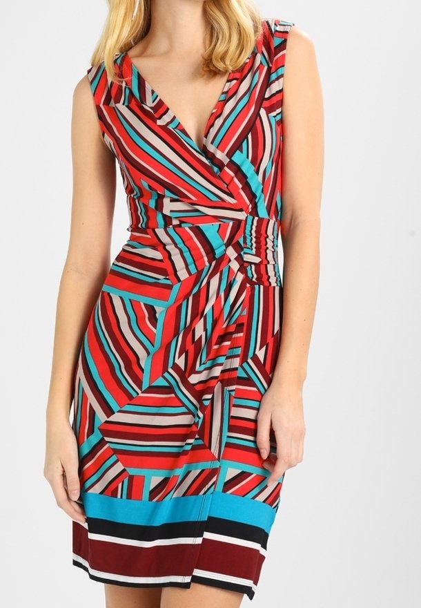 Robe portefeuille sans manches avec col en V en rayures géométriques rouges, bleu sarcelle, noires et beiges, cintrée à la taille, longueur au genou.