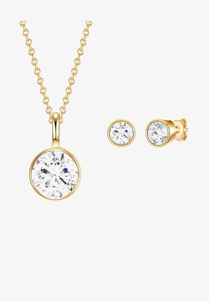 Juego de joyería en tono dorado que incluye un collar con un colgante redondo que tiene una gran piedra clara y pendientes tipo studs a juego con piedras claras más pequeñas.