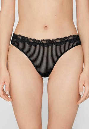 Černé spodní prádlo s vroubkovaným síťovaným vzorem, zdobené vroubkovaným krajkovým pásem a měkkým elastickým lemováním. Oblečení má střední výšku pasu a je průsvitné.