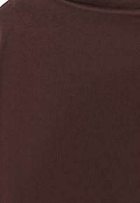 Gros plan d’un tissu lisse brun foncé montrant une texture fine et sans motifs ou détails visibles.