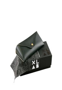 Svart läderfodral med rundad klaff, guldknappstängning. Åtföljs av en svart låda med vita geometriska mönster och text.
