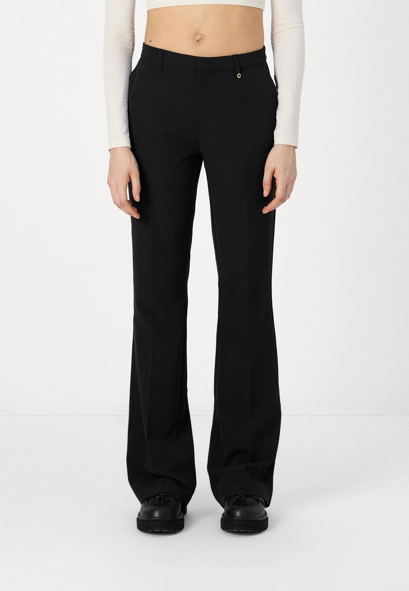Pantalons évasés noirs en tissu lisse, dotés d'une fermeture éclair, de poches avant et d'un subtil accent métallique au-dessus de la taille.