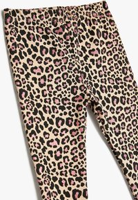 Legginsy w wzór panterki z jasnobrązową bazą, czarnymi plamkami i różowymi błyszczącymi akcentami. Elastyczny pas zapewniający komfort i swobodę ruchów.