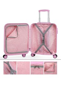 Maleta dura rosa con interior de patrón geométrico, mango retráctil y cuatro ruedas. Cuenta con un bolsillo con cremallera y correas de sujeción.