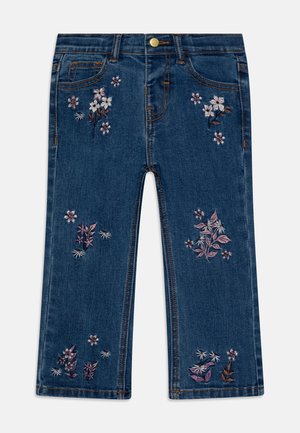 Children’s blue denim jeans with pink and white floral embroidery on front legs, brass button closure, and five-pocket design.