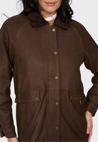 Brązowa skórzana kurtka z kołnierzem z sztruksu, z zatrzaskami i bocznymi kieszeniami. Charakteryzuje się gładką teksturą oraz dopasowanym, strukturalnym krojem.