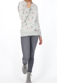 Light gray sweatshirt with pink floral pattern, ribbed cuffs, and hem. Paired with gray skinny jeans and lace-up gray boots.