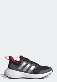 Zapatilla deportiva negra con parte superior de malla, acentos rojos y detalles en tres franjas plateadas. Cuenta con una suela acolchada y un agarre de goma texturizada.