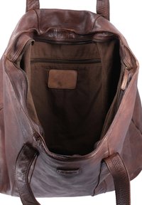 Brown leather tote bag with a spacious, unlined interior, featuring a zipper pocket and a small embossed brand tag inside.