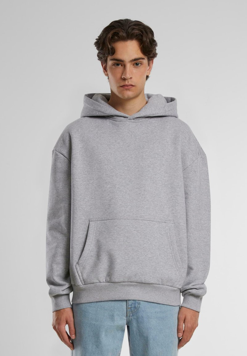 Grå hettegenser med kengurulomme, løs passform, ribbestrikkede ermer og nederkant. Laget av myk, teksturert stoff, som komplimenterer lyseblå jeans.