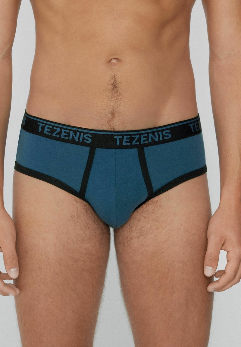 Blaue und schwarze Herrenbriefunterwäsche mit einem schwarzen Bund, der das Logo "TEZENIS" trägt. Der Stoff erscheint glatt und hat minimale Nähdetails.
