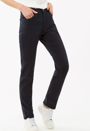 Pantaloni blu scuro a taglio slim, realizzati in tessuto misto cotone. Presentano tasche laterali e chiusura con zip. Abbinati a sneakers bianche.