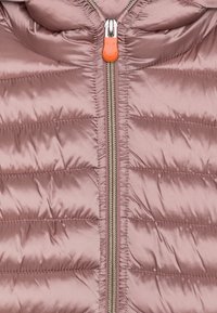 Polstret jakke i blød lyserød stof, med en lynlås foran med orange trækrem og diskret vandret syninger for ekstra tekstur.