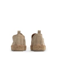 Beige suede shoes with a closed back, featuring a woven jute sole and a small pull tab at the heel. Simple design without embellishments.