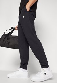 Donkergrijze sweatpants van katoen met elastische boorden. Draag het met witte sneakers en houd een zwarte sporttas vast. Eenvoudig wit logo detail.
