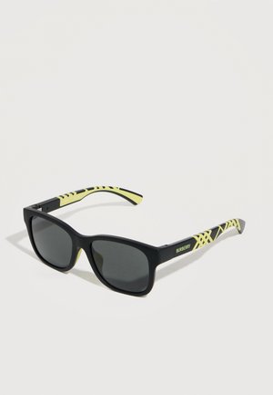 Gafas de sol negras con lentes oscuras, con brazos estampados en amarillo y negro y el logo "BURBERRY" en el lateral.