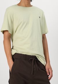 Ljusgrön bomullströja med avslappnad passform, rund halsringning och korta ärmar. Har en liten svart logotyp på bröstet.