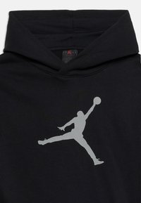 Μαύρο φούτερ με κουκούλα με μεγάλο γκρι λογότυπο Jumpman, που απεικονίζει παίκτη μπάσκετ να πηδά με την μπάλα τεντωμένη πάνω από το κεφάλι στο στήθος.