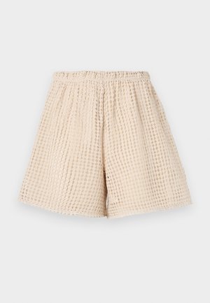 Beige shorts med et teksturert, vaffelmønster. Elastisk liv og løs passform. Midt på låret lengde. Lett materiale.