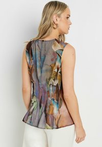Top senza maniche in tessuto trasparente con un motivo floreale multicolore, orlo leggermente svasato e chiusura con bottone sul retro.