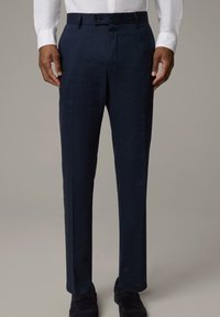 Mörkblå byxor i ett lätt material med en slät yta. Har knappstängning och sidofickor, skräddarsydd passform, med en diskret lyster.