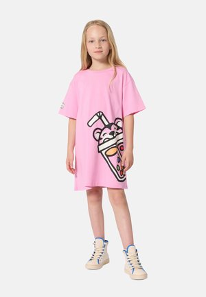 Rosa übergroßes T-Shirt-Kleid mit einer Grafik eines Bären, der ein Getränk hält, mit farbenfrohen Akzenten. Kombiniert mit cremefarbenen High-Top-Sneakern.