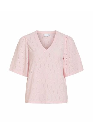 Blouse rose pâle avec col en V, manches courtes bouffantes et motif géométrique texturé sur le tissu.