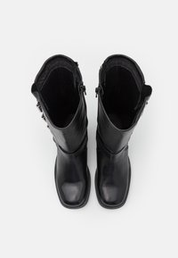 Black leather knee-high boots with a smooth finish, rounded toes, and side zippers. Interior features soft lining for comfort.