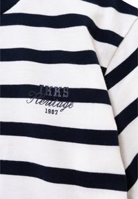 Camisa de algodón a rayas en azul marino y blanco con cuello redondo. Cuenta con texto bordado "IKKS Heritage 1987" en azul en la parte delantera.